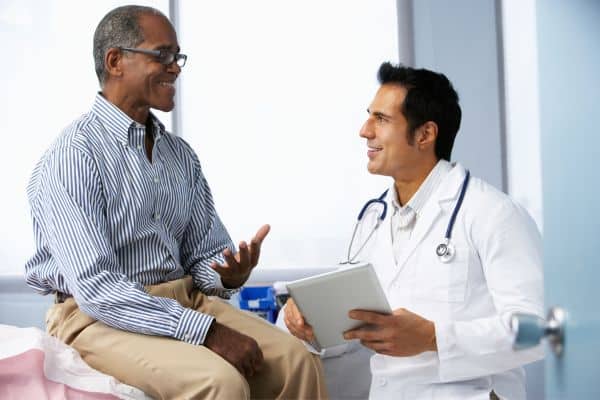 A male patient sitting on an examination table in his doctors office discussing hypertension treatment