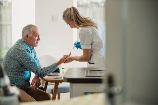 A man in a geriatric medicine doctor's office having his blood sugar tested