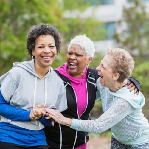 A group of older women laughing while hiking showing good health after being seen by geriatric medicine doctor