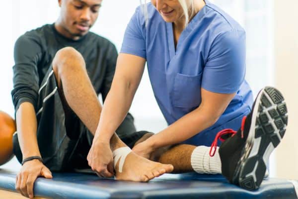 An athlete having his ankle wrapped by his sports medicine doctor.