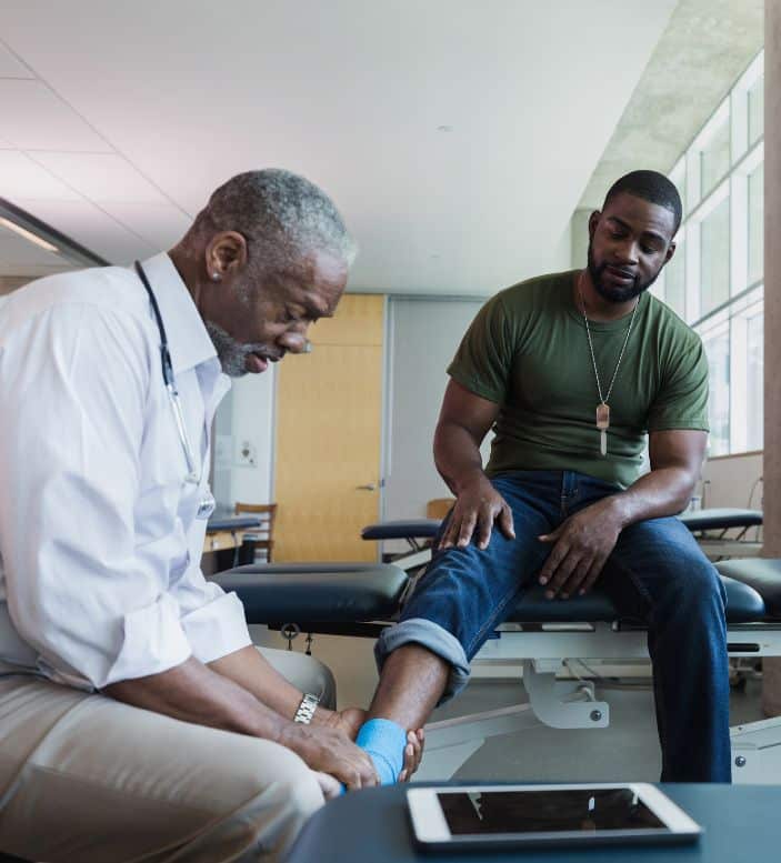 An athlete having his ankle wrapped by a physician