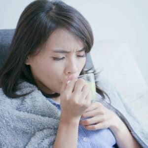 A woman drinking tea with the flu