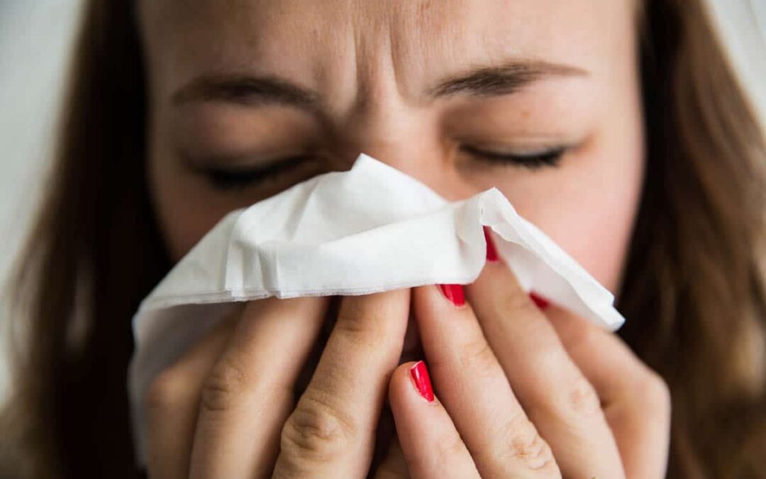 A woman blowing her nose into a tissue