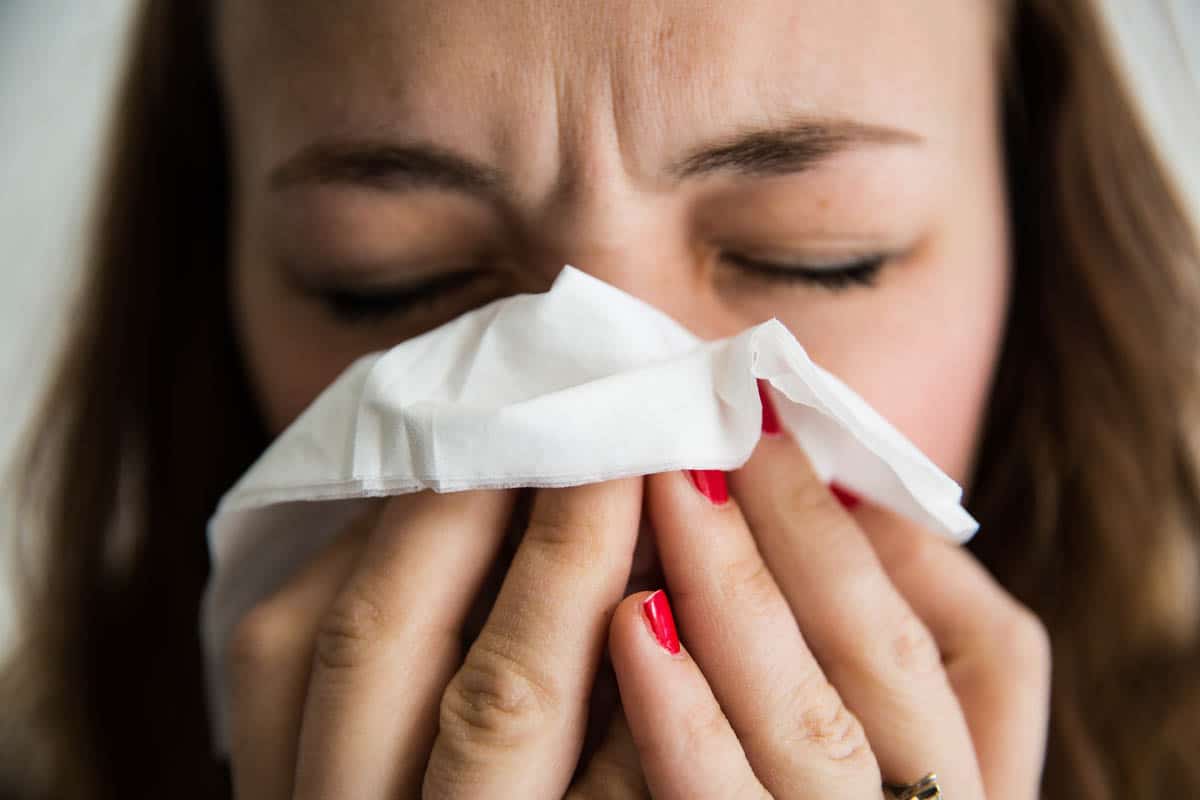 A woman blowing her nose into a tissue